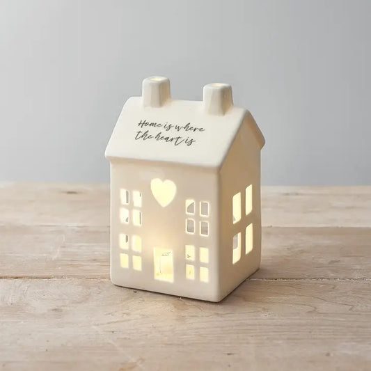 Pyntehus til lys i hvit keramikk med sitat på take: "Home is where your heart is".  Det følger med LED-lyd.