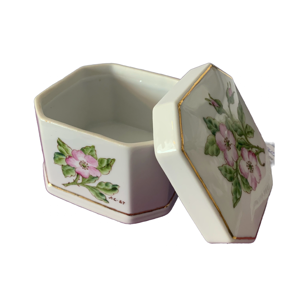 Fin liten porselensboks til oppbevaring av småting. Blomstermotiv i lys rosa og grønne blader, gullkant rundt boksen og på lokket.